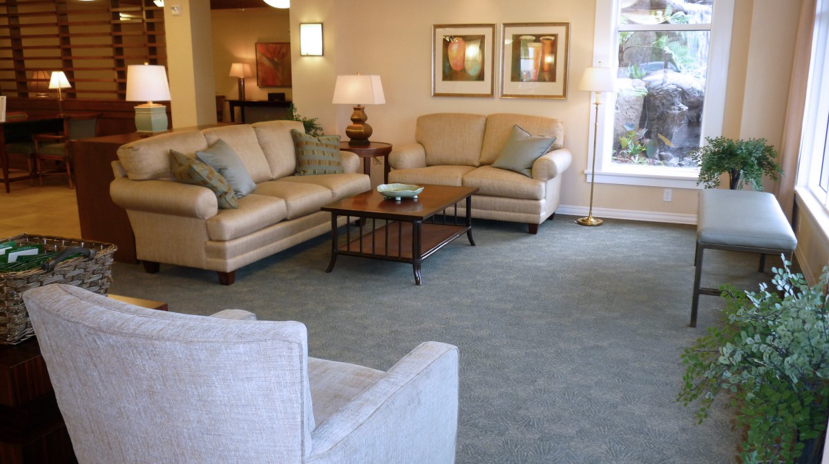 A cozy living room with comfortable sofas and a coffee table, featuring warm lighting and decorative artwork.