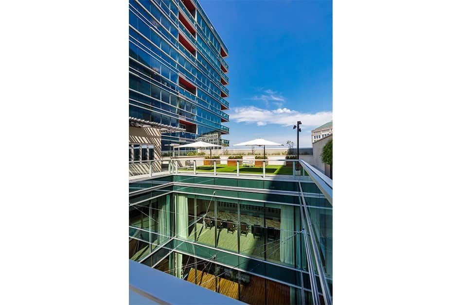 A modern office building with a glass facade and an open outdoor space under a clear blue sky.