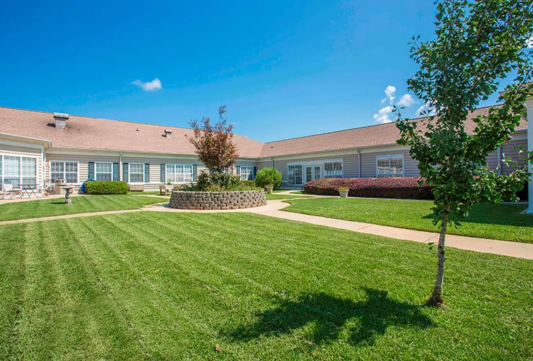 A well-maintained building with a green lawn and clear blue sky.