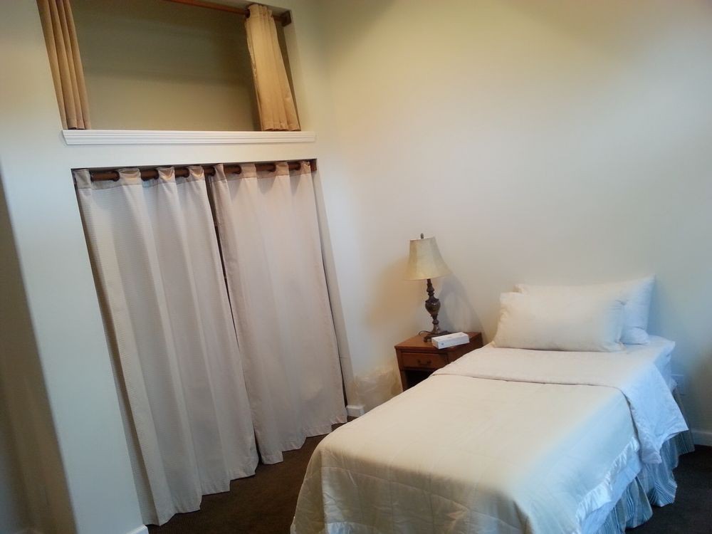 A minimalist bedroom with a single bed and neutral color scheme.