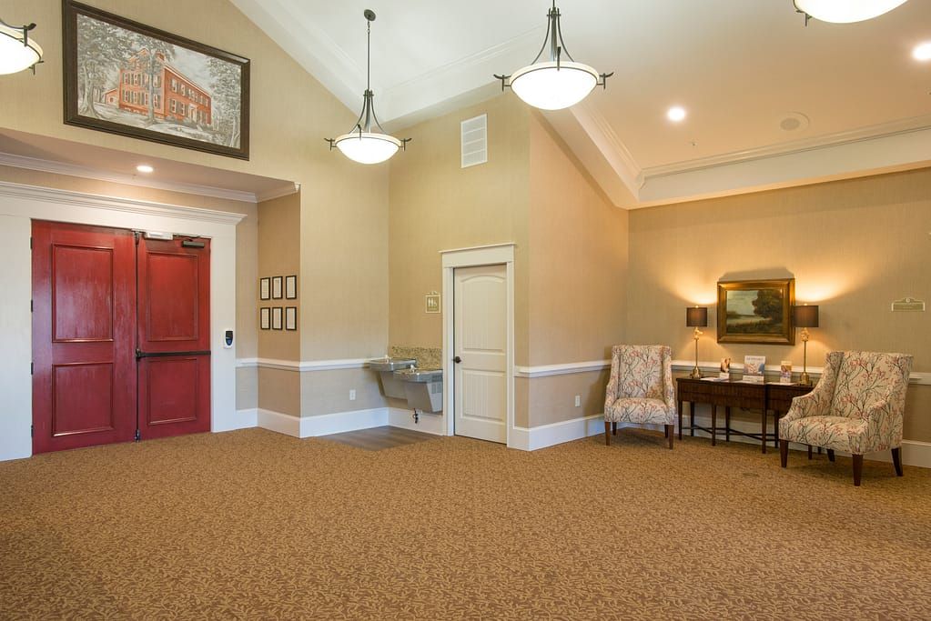 A warm and inviting lobby with elegant decor, featuring chandeliers, a red door, and comfortable furniture.