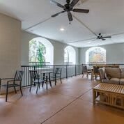 A covered patio with various seating options and ceiling fans.