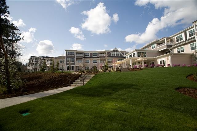 A large building with a well-maintained lawn and steps under a partly cloudy sky.
