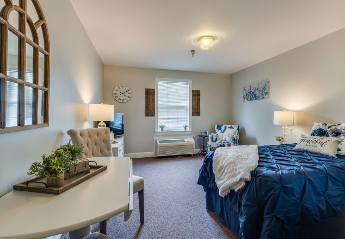 A cozy bedroom with neutral tones, featuring a comfortable bed, two lamps, and decorative wall art.