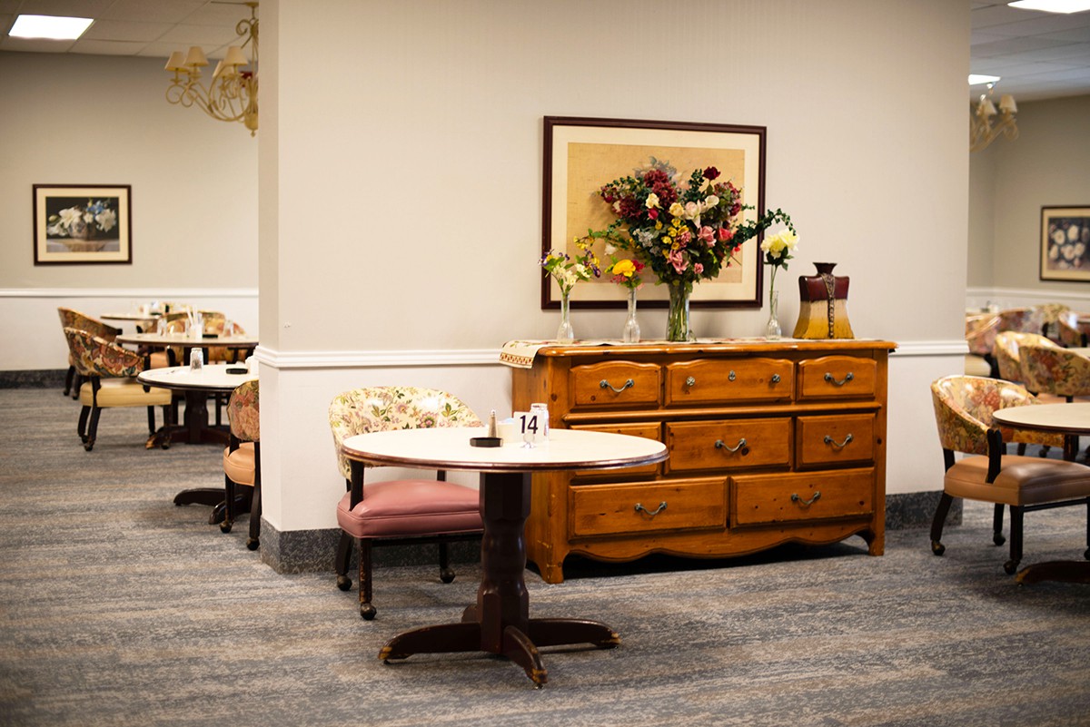 A cozy interior with a wooden dresser and small table adorned with flowers.