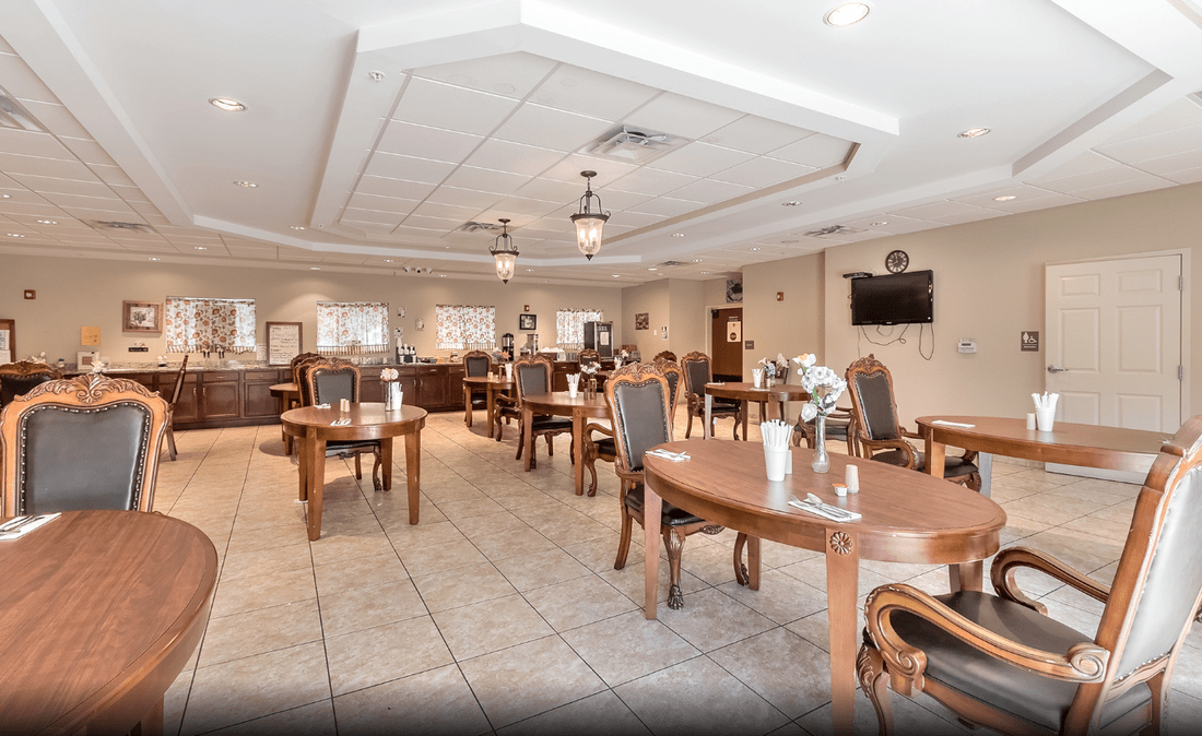 A spacious and elegantly decorated dining area with wooden tables and chairs, well-lit by overhead lighting.