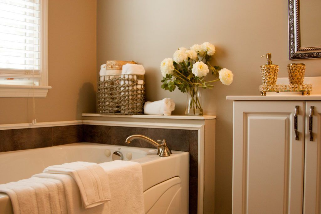 A luxurious bathroom with a tub, neatly folded towels, and a vase of white flowers.