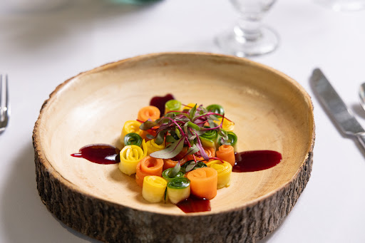 A beautifully plated dish featuring an array of colorful vegetables, drizzled with a rich sauce.