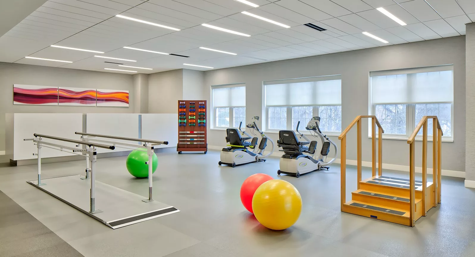 A well-equipped rehabilitation and physical therapy room featuring exercise bikes and colorful fitness balls.