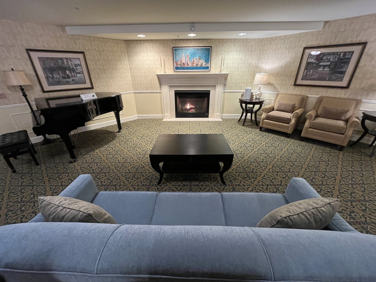 A cozy living room with a fireplace, sofa, and piano.