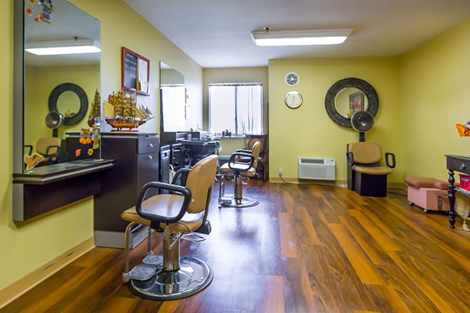 An interior view of a hair salon featuring chairs, mirrors, and wooden flooring.