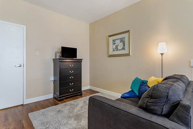 A cozy living room with a sofa, dresser, and a small television.