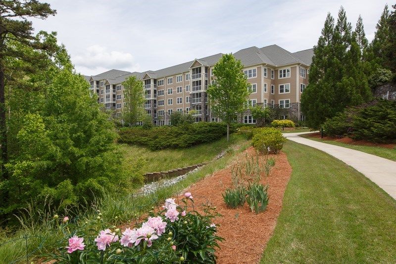 A scenic view of an apartment building surrounded by landscaped gardens and a walkway.