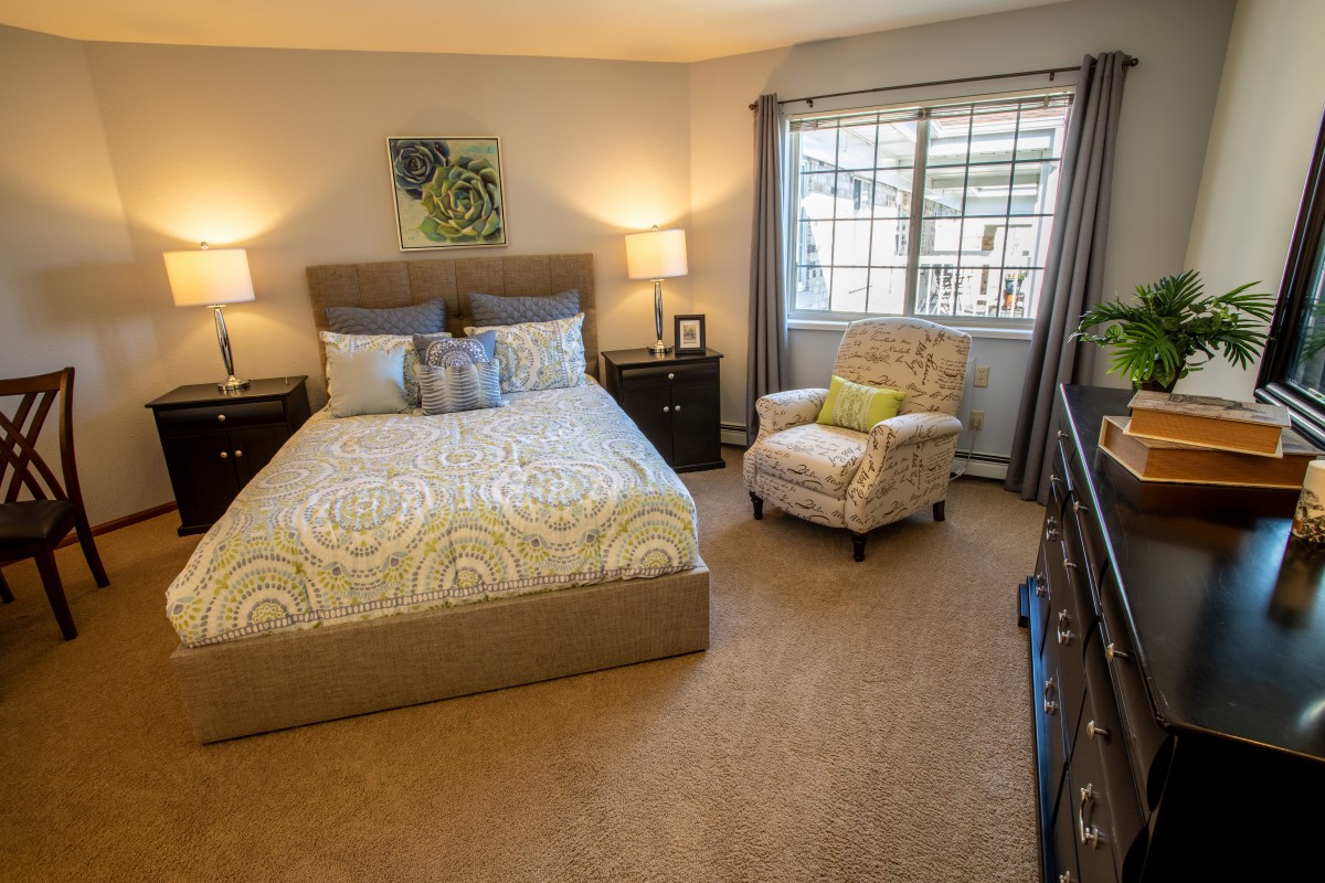 A cozy bedroom with modern decor, featuring a comfortable bed and a stylish armchair by the window.