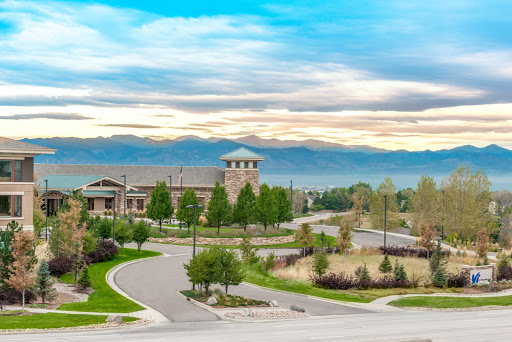 A picturesque view of a modern building surrounded by lush greenery and mountains in the background.