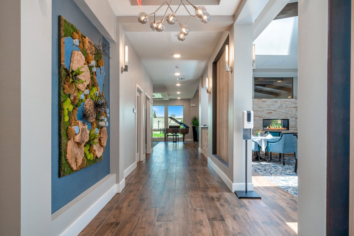 A modern hallway with wooden flooring, contemporary artwork, and ample natural light.