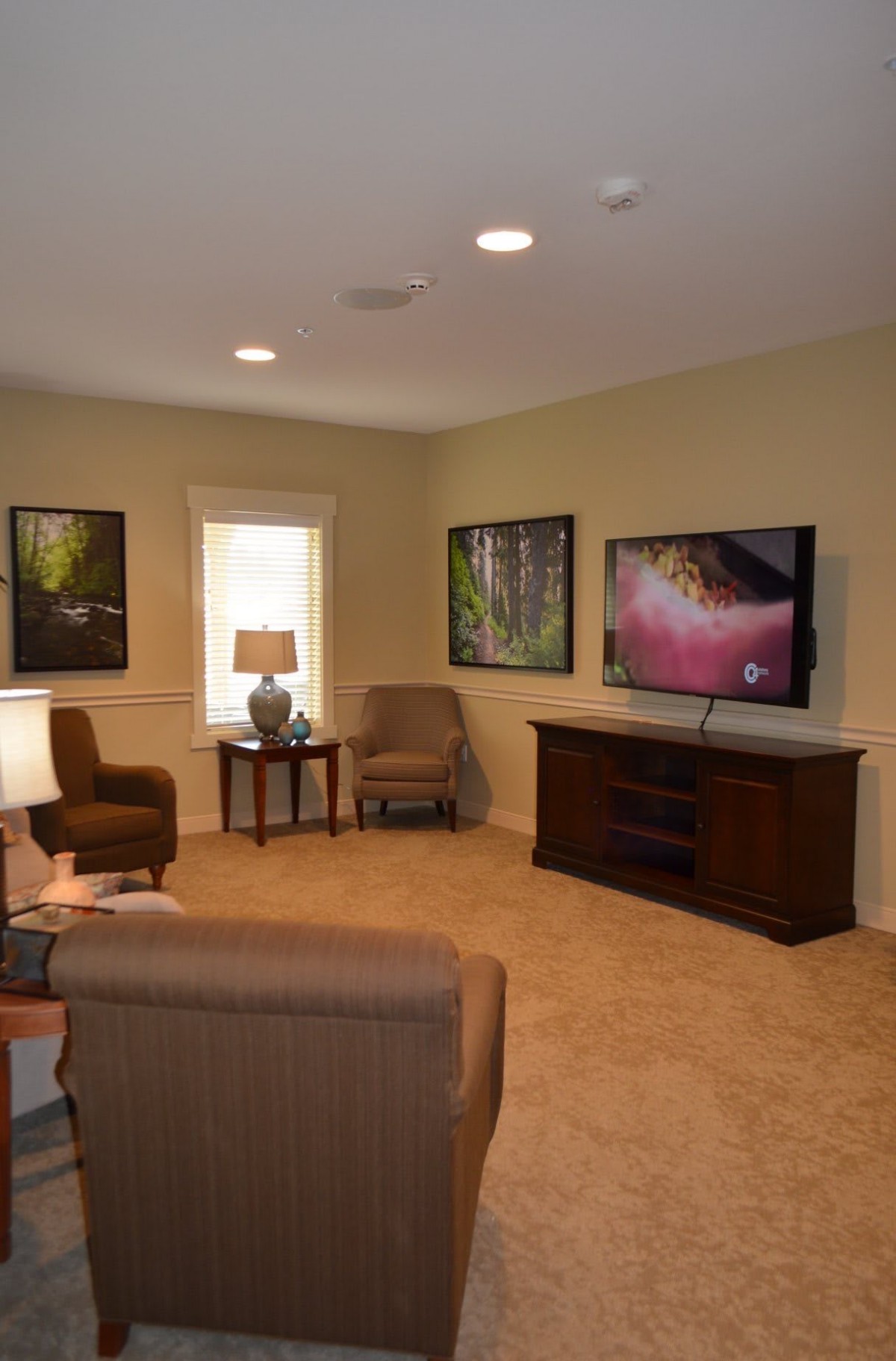 A cozy living room with comfortable seating, a television, and framed artwork on the walls.