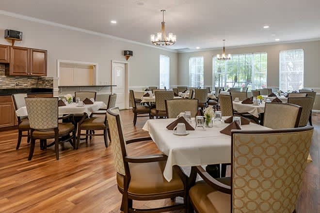 A well-organized dining area with neatly set tables and comfortable chairs under elegant chandeliers.