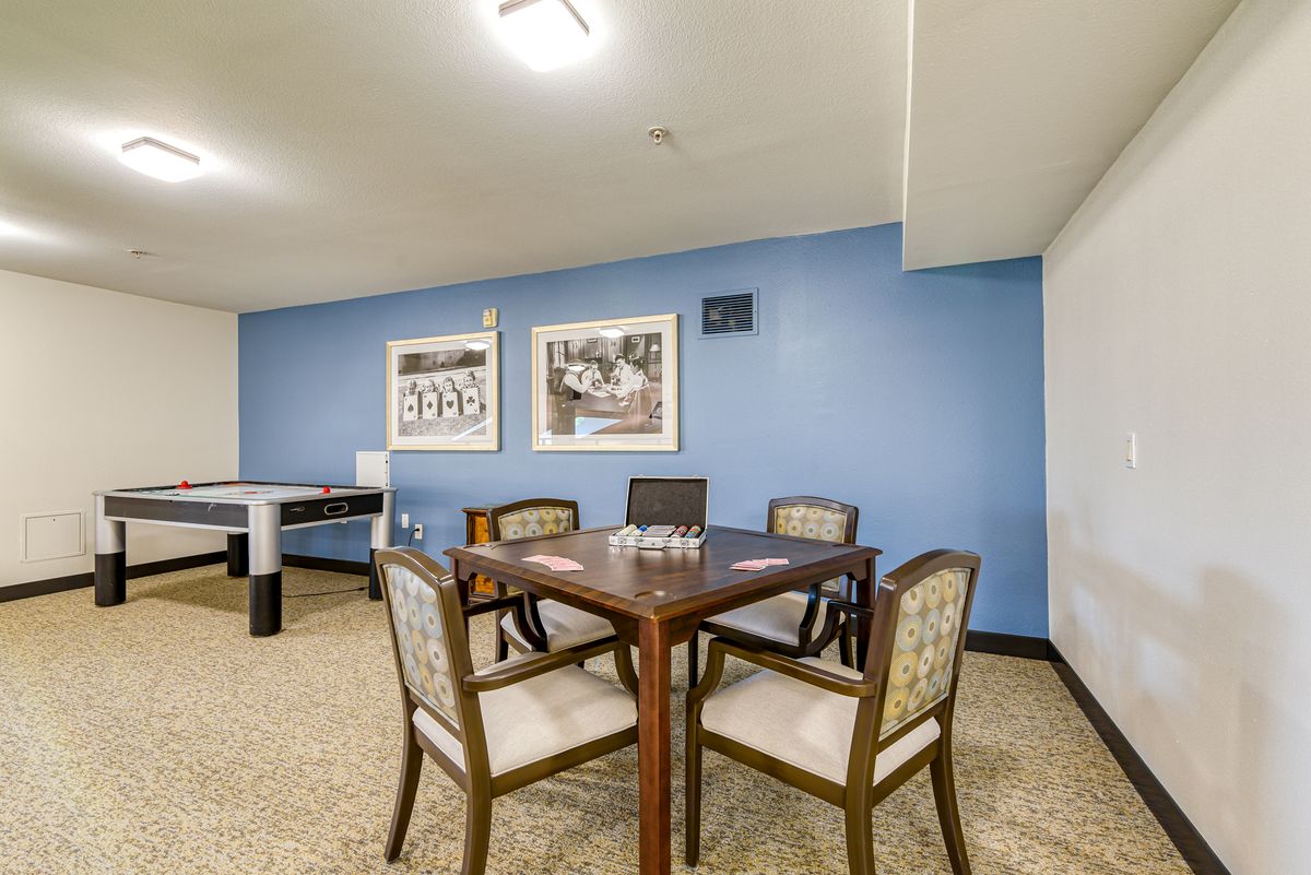 A game room featuring a table and chairs, with artwork on a blue accent wall.