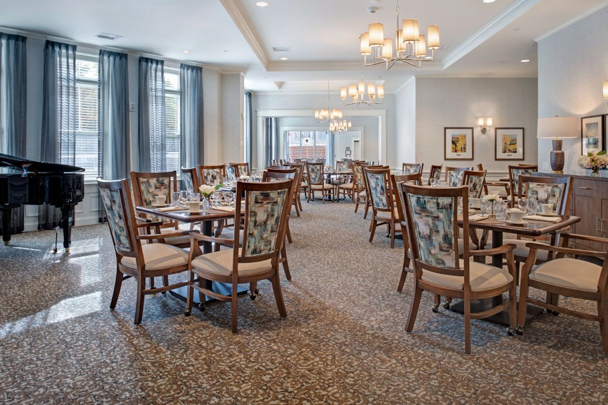 A spacious dining area with elegantly arranged tables and chairs, featuring classic chandeliers and tasteful decor.