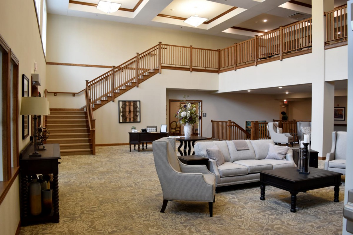 A modern and spacious lobby with elegant furniture and wooden stairs.