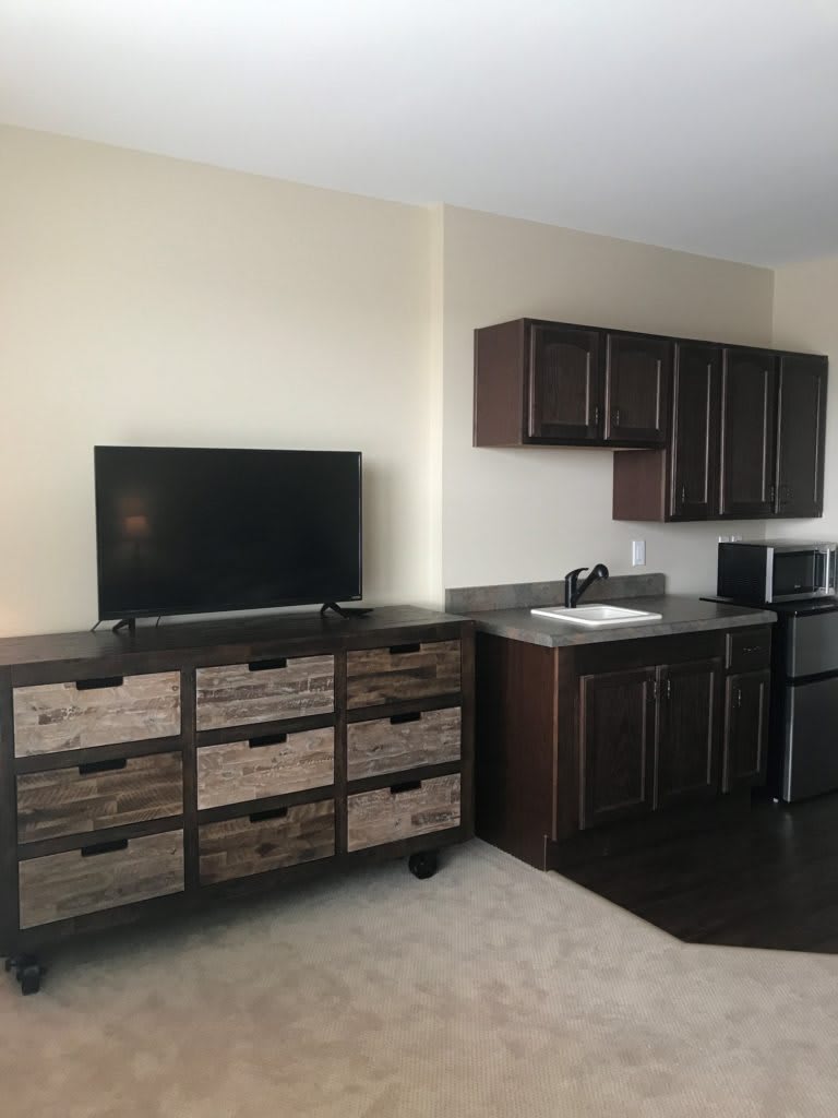 A modern kitchen with dark cabinets, a TV, and appliances.