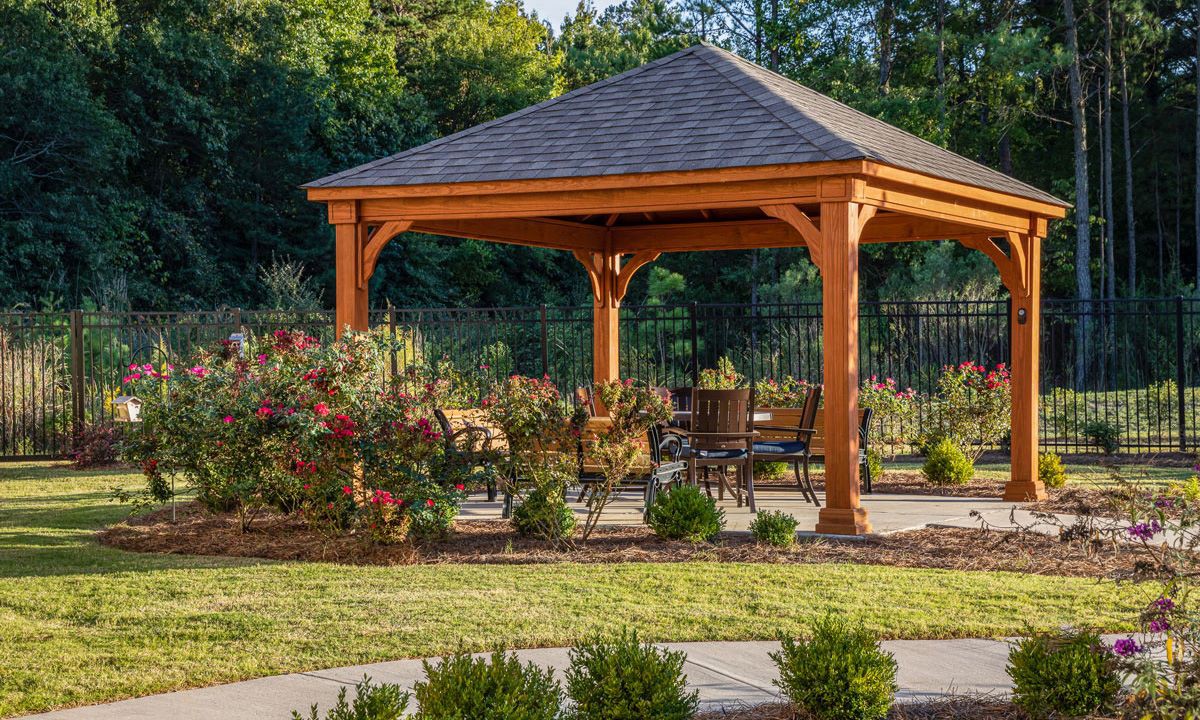 A wooden gazebo with seating, surrounded by a landscaped garden.