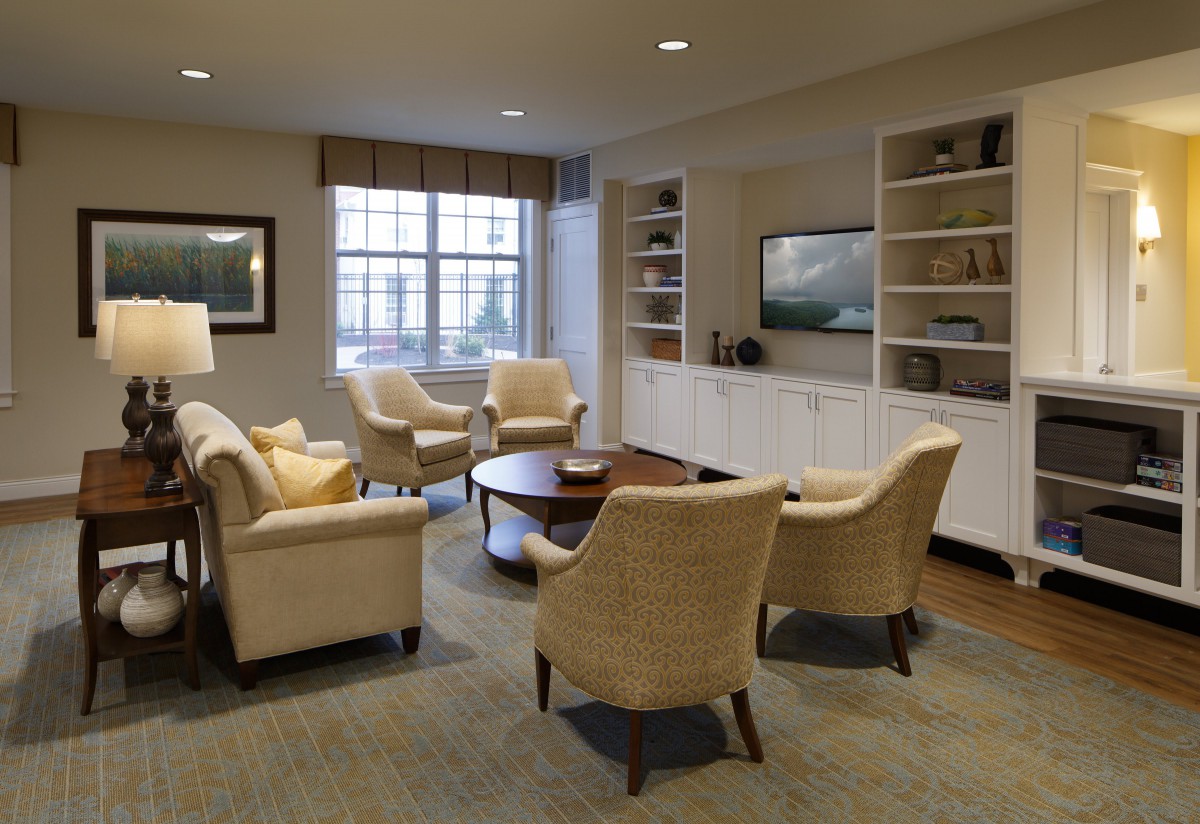 A cozy living room with comfortable seating, a round table, built-in shelves, and a television.