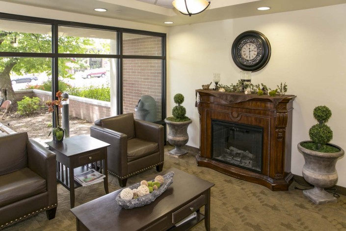 A cozy waiting room featuring a fireplace, armchair, and stylish decor.