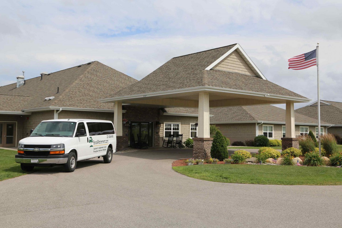 A building entrance with a covered driveway and a parked van.