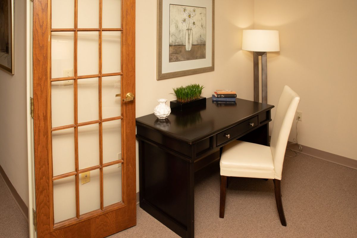 A cozy home office setup with a dark wood desk, comfortable chair, and ambient lighting.