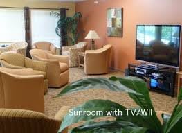 A cozy sunroom featuring comfortable seating and a TV.