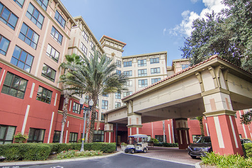 A welcoming entrance to a hotel, featuring palm trees and a clear blue sky.
