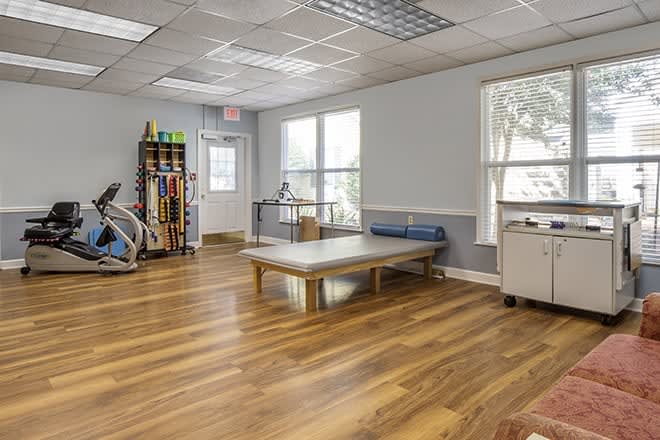 A spacious therapy room with exercise equipment and natural lighting.