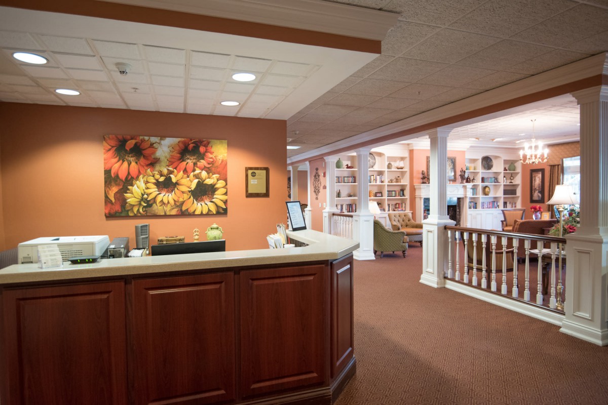 A well-lit reception area featuring a wooden desk and vibrant artwork on the wall.