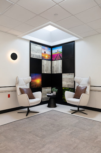 A modern lounge area featuring two stylish chairs, a small table, and vibrant wall art.