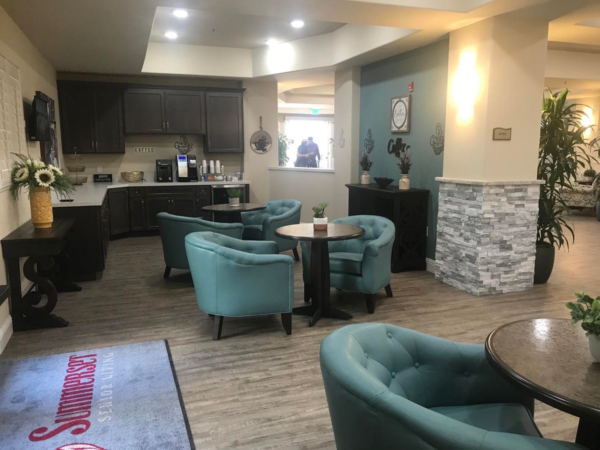 A cozy lounge area with teal armchairs and small coffee tables, complemented by modern decor and soft lighting.
