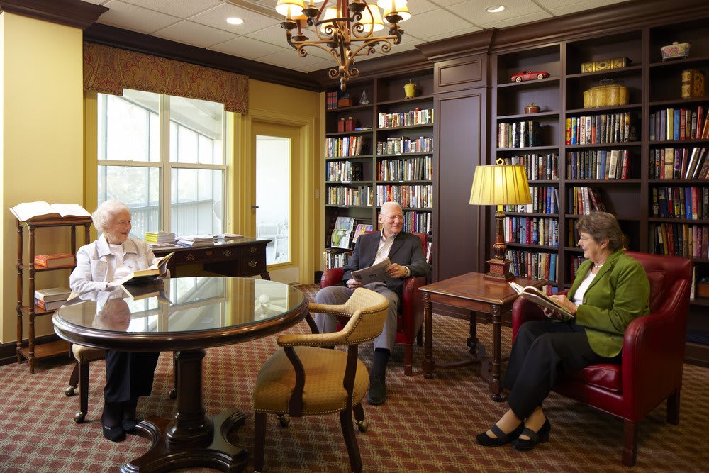 A cozy library room with people engaged in reading and conversation.