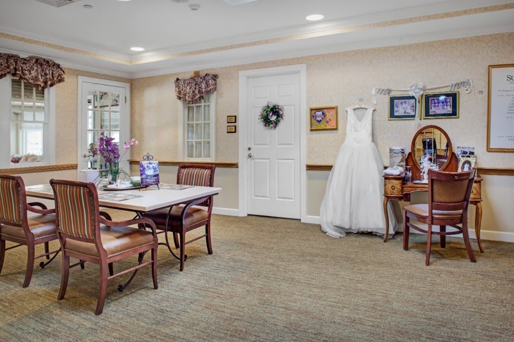 A cozy living room with a wedding dress on display, featuring elegant furniture and wall decor.