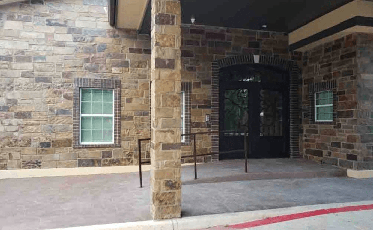 A building entrance with a stone wall and a window.