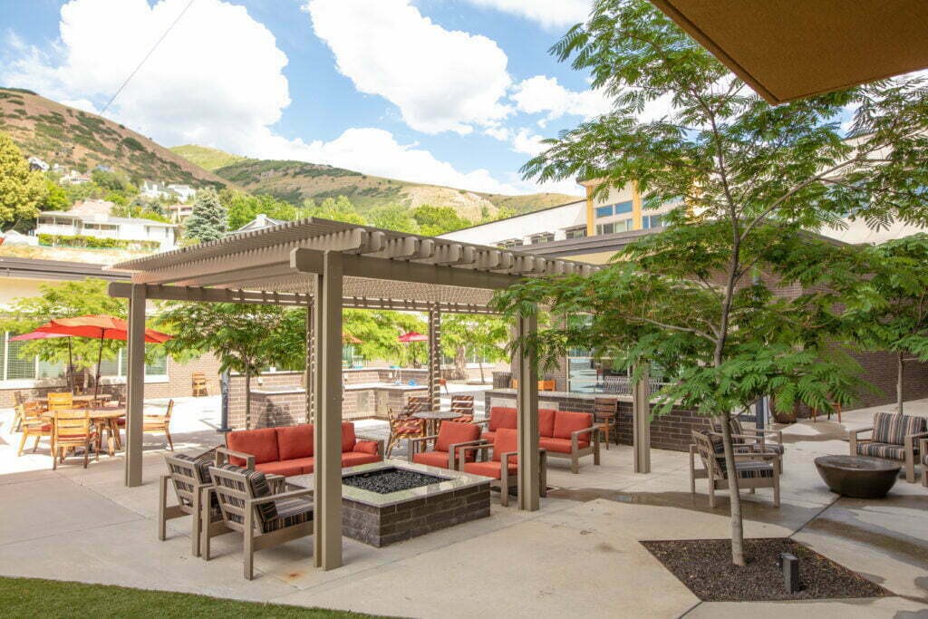 A scenic outdoor patio with a pergola, surrounded by trees and mountains.