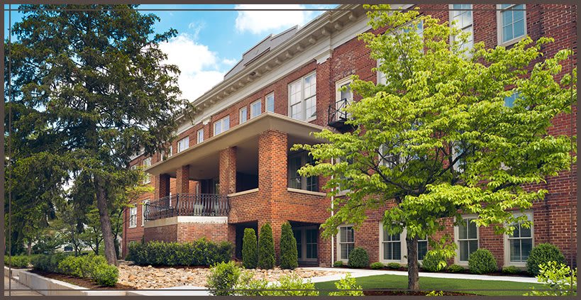 A residential building with brick facade surrounded by greenery.