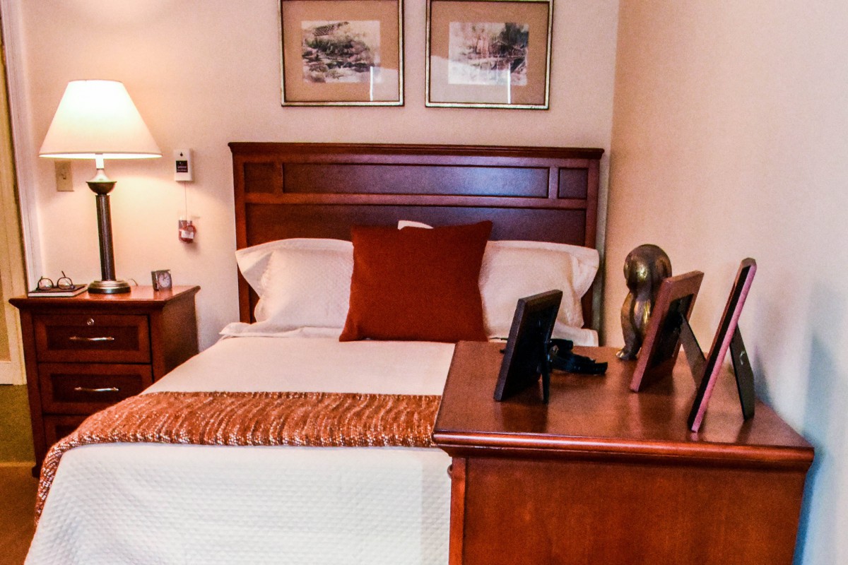 A cozy bedroom with a neatly made bed, flanked by nightstands and decorated with framed artwork on the wall.