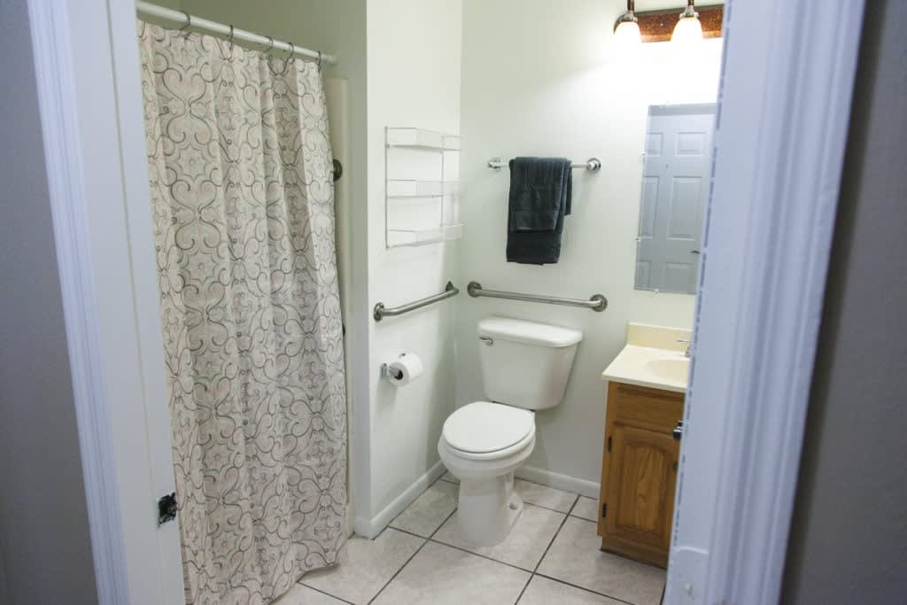 A clean and tidy bathroom featuring a toilet, sink, and shower with a patterned curtain.