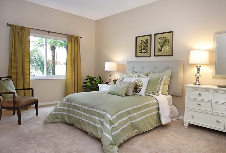 A cozy bedroom with green bedding and soft lighting.