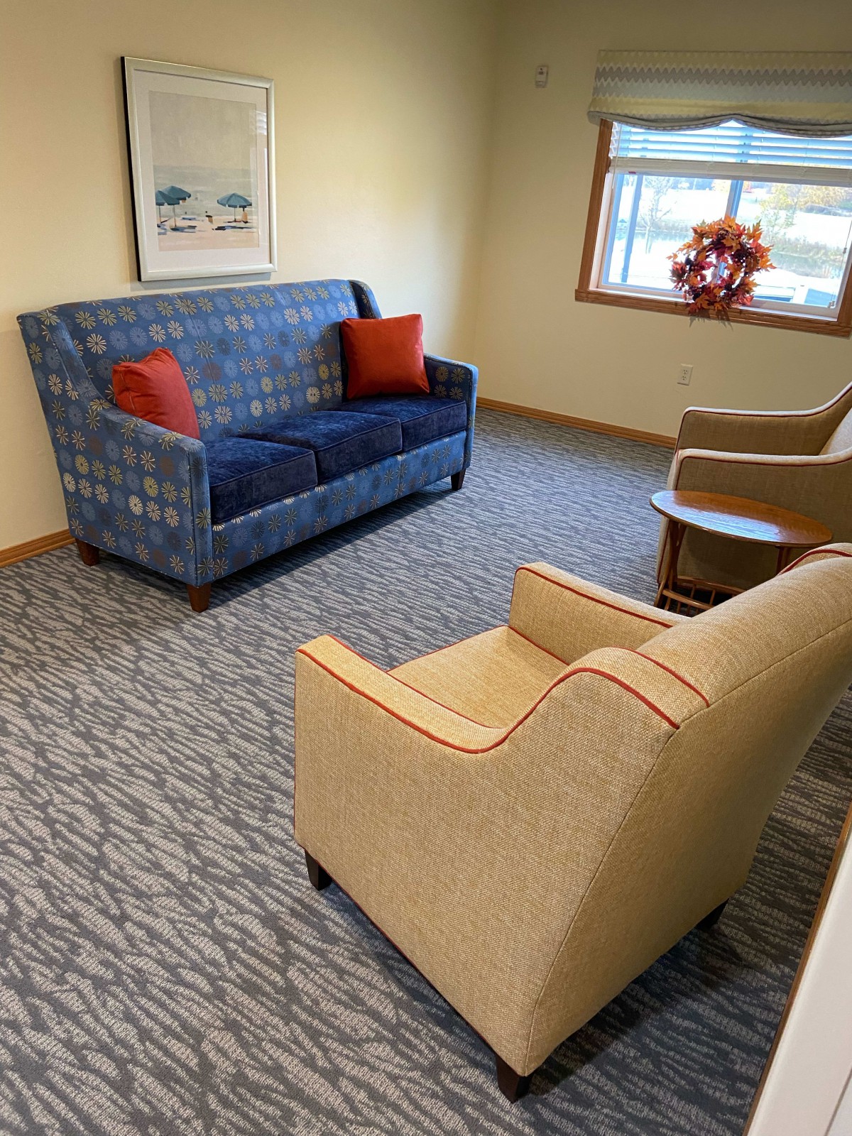A cozy living room setting with a blue sofa, red cushions, and two beige armchairs.