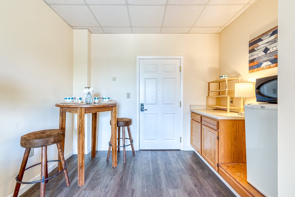A minimalist room with a wooden table, stools, and a cabinet next to a door.