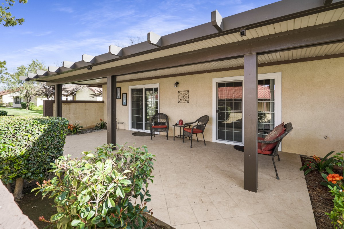 A covered patio with outdoor seating and a garden view.