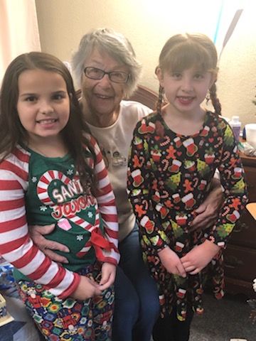 An adult and two children dressed in festive holiday attire, smiling indoors.