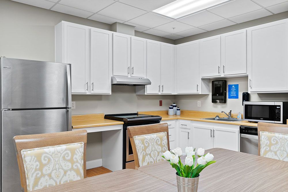 A modern kitchen with white cabinets, stainless steel appliances, and a table with decorative flowers.